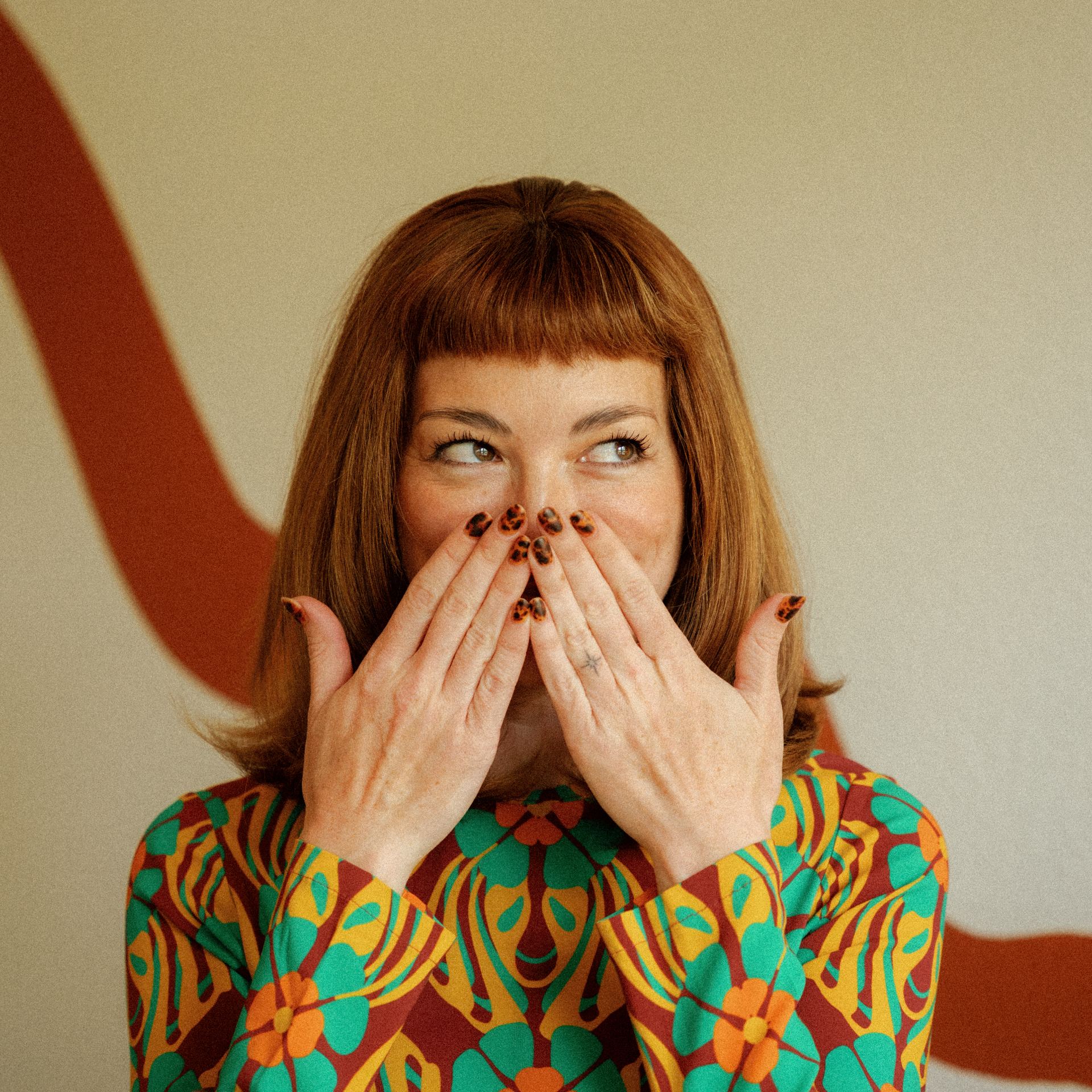 Kira laughing, leopard-print nails to her face